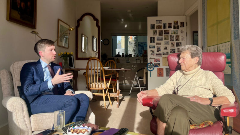 Dan and Hedi converse in her home