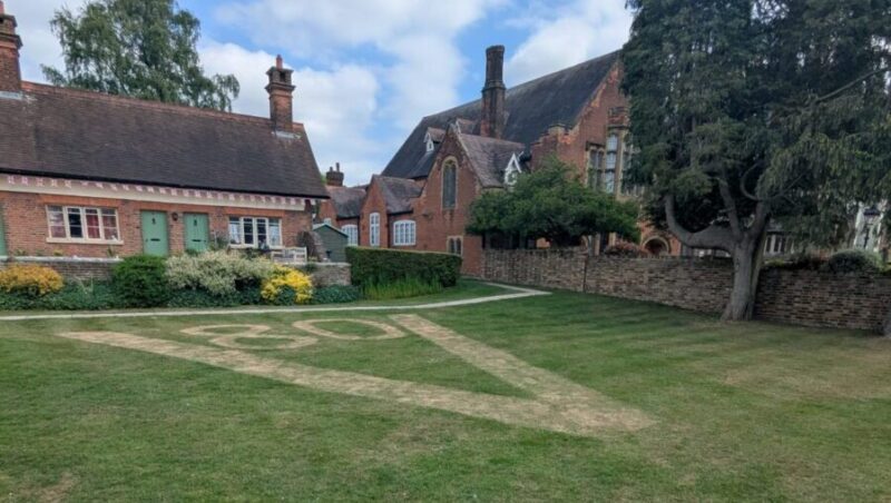 A large V and the number 80 cut into the lawn of the Alms Houses